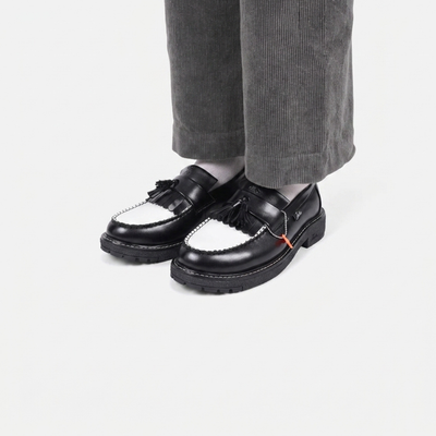 Black loafers worn with gray pants on a white background