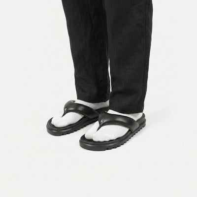 Black and white sandals worn with black pants on a white background