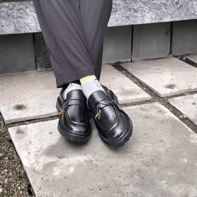Person wearing black shoes with thick soles on a concrete surface.