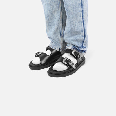 Black and white sandals worn with light blue jeans on a white background