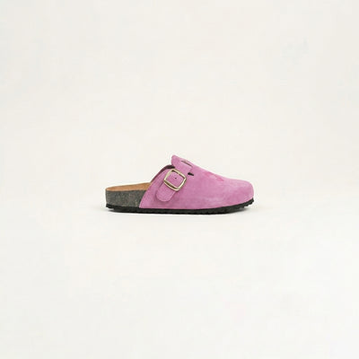 Pink suede clog shoe with a gold buckle on a light beige background