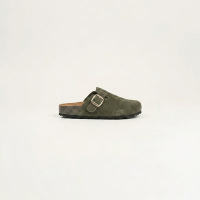 Green suede clog shoe with a gold buckle on a light gray background