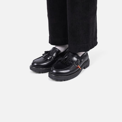 Black loafers worn with black pants on a white background