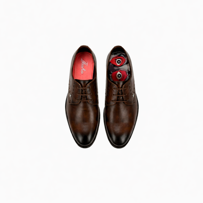 Pair of brown dress shoes with red lining on a white background