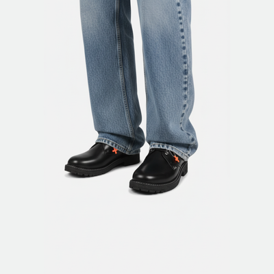 Black shoes with orange accents worn with blue jeans on a white background