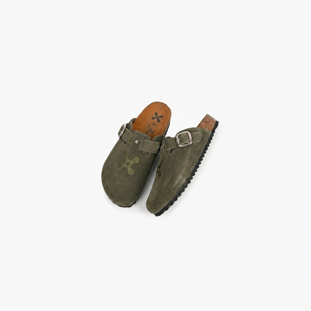 Pair of green suede shoes with brown soles on a white background