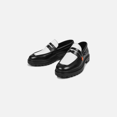 Black loafers with white soles on a light gray background