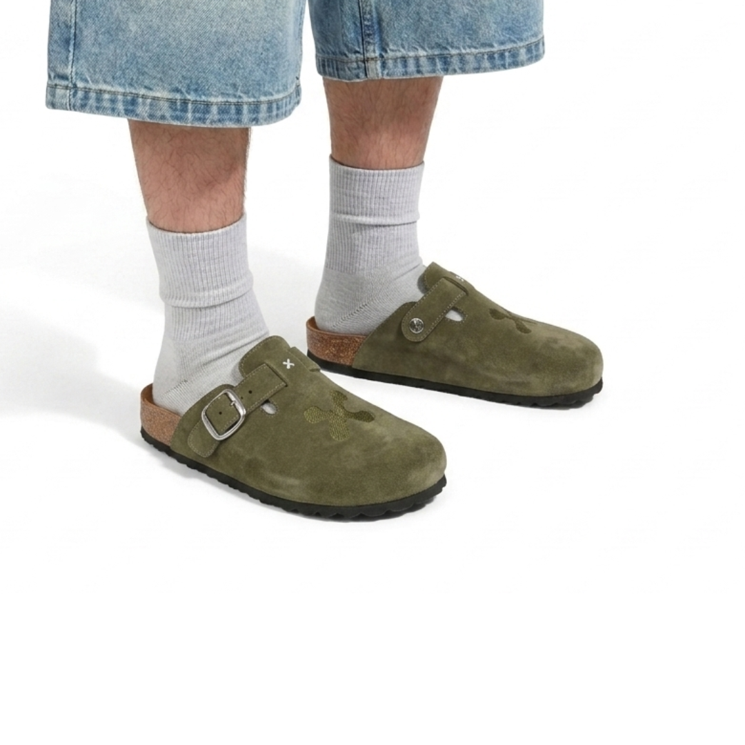 Green suede clogs worn with light gray socks on a white background