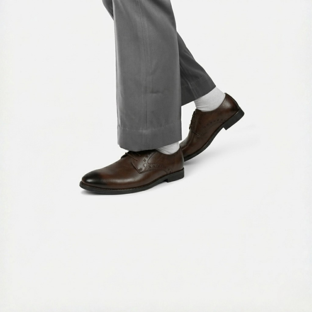Black dress shoes worn with gray pants on a white background