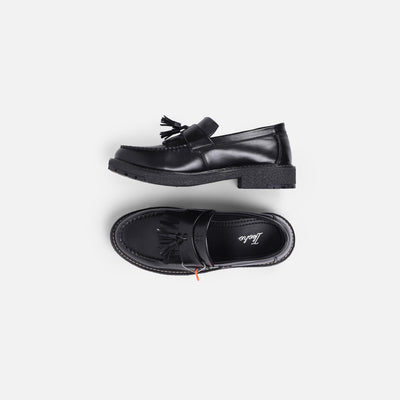 Black loafers with tassels on a white background