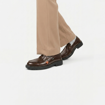 Brown loafers worn with beige pants on a white background