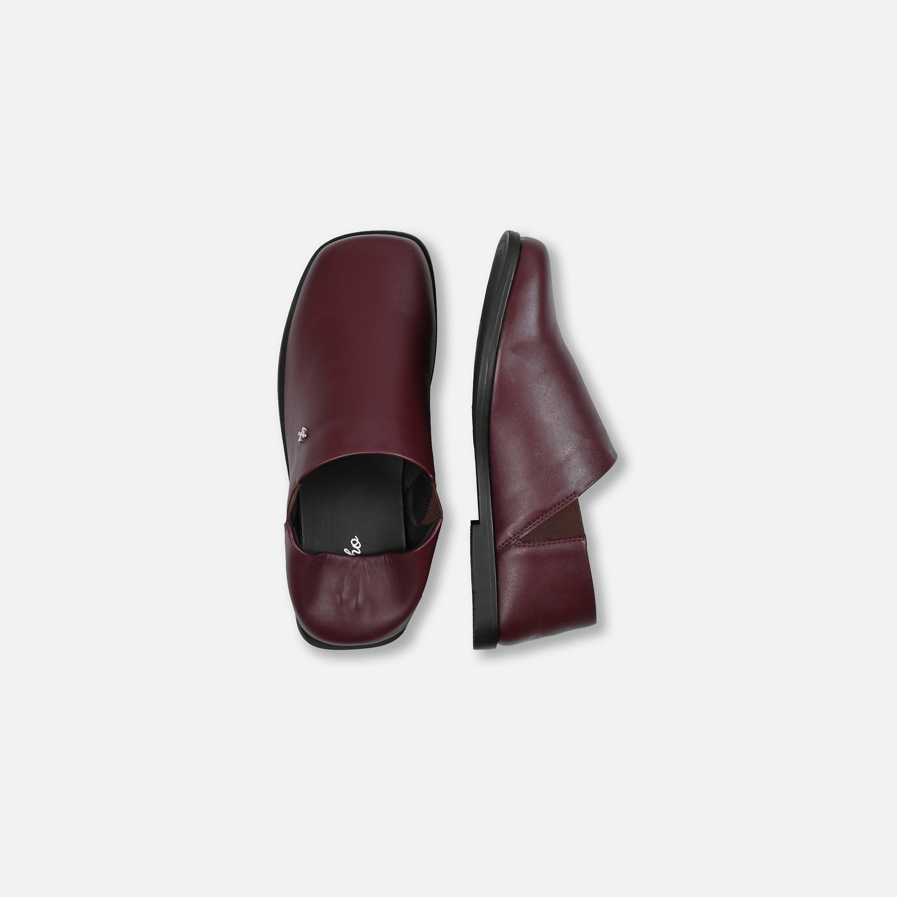 Pair of maroon leather shoes on a light gray background