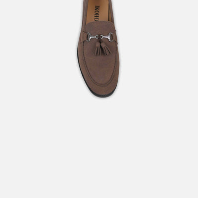 Brown suede loafer with a tassel on a light gray background