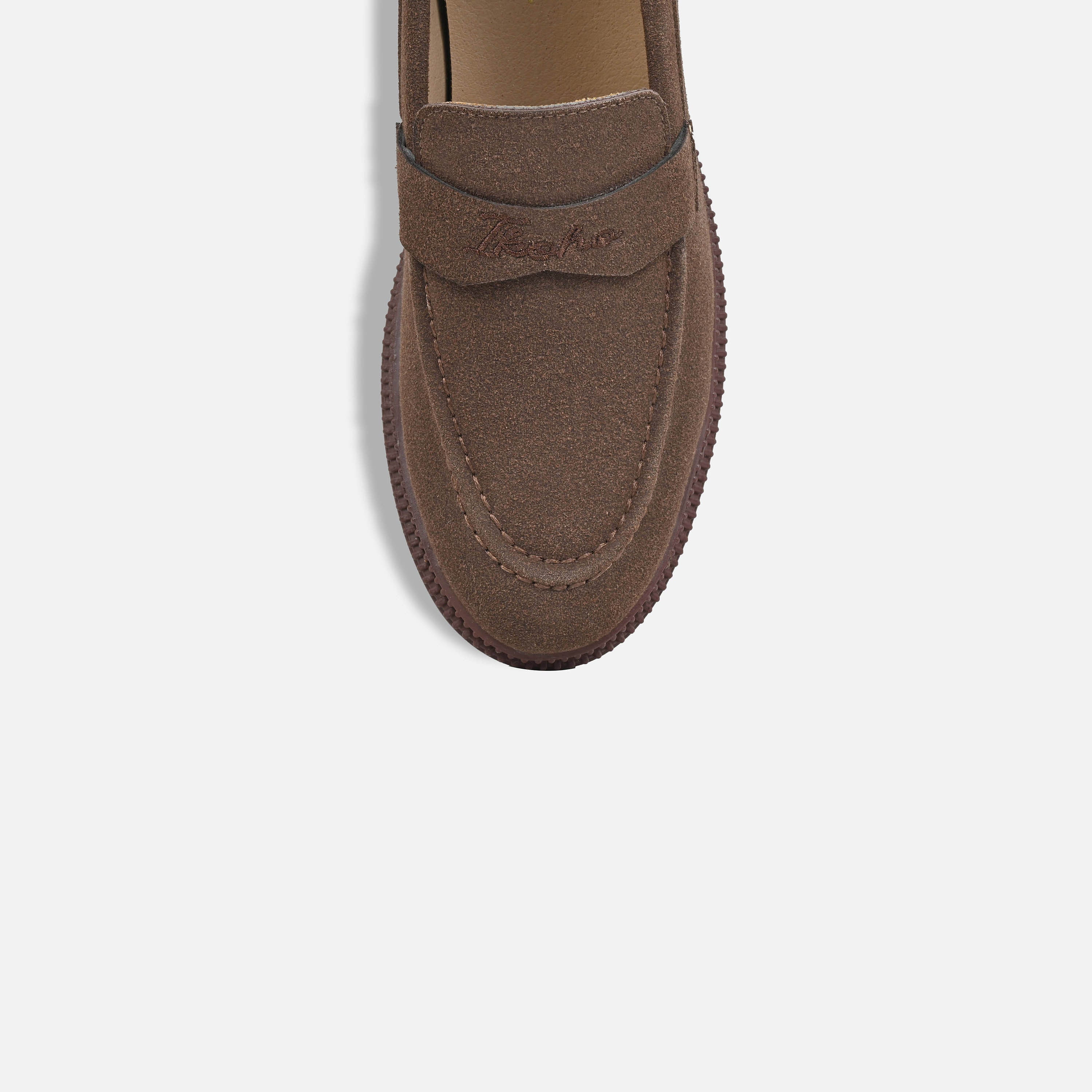 A top-down view of a brown suede penny loafer on a light gray background.