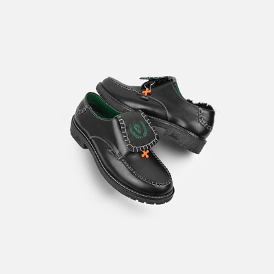 Black dress shoes with green lining and orange accents on a light gray background