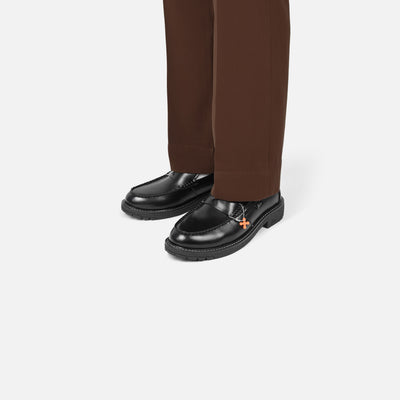 Black loafers worn with brown pants on a white background