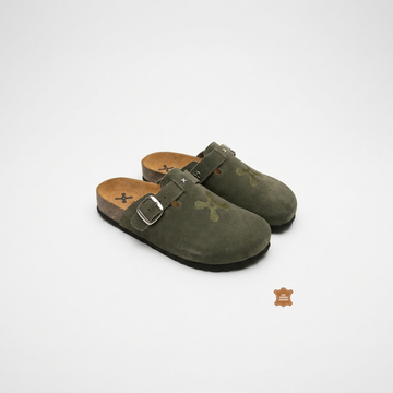 Pair of green suede clogs with brown soles on a white background