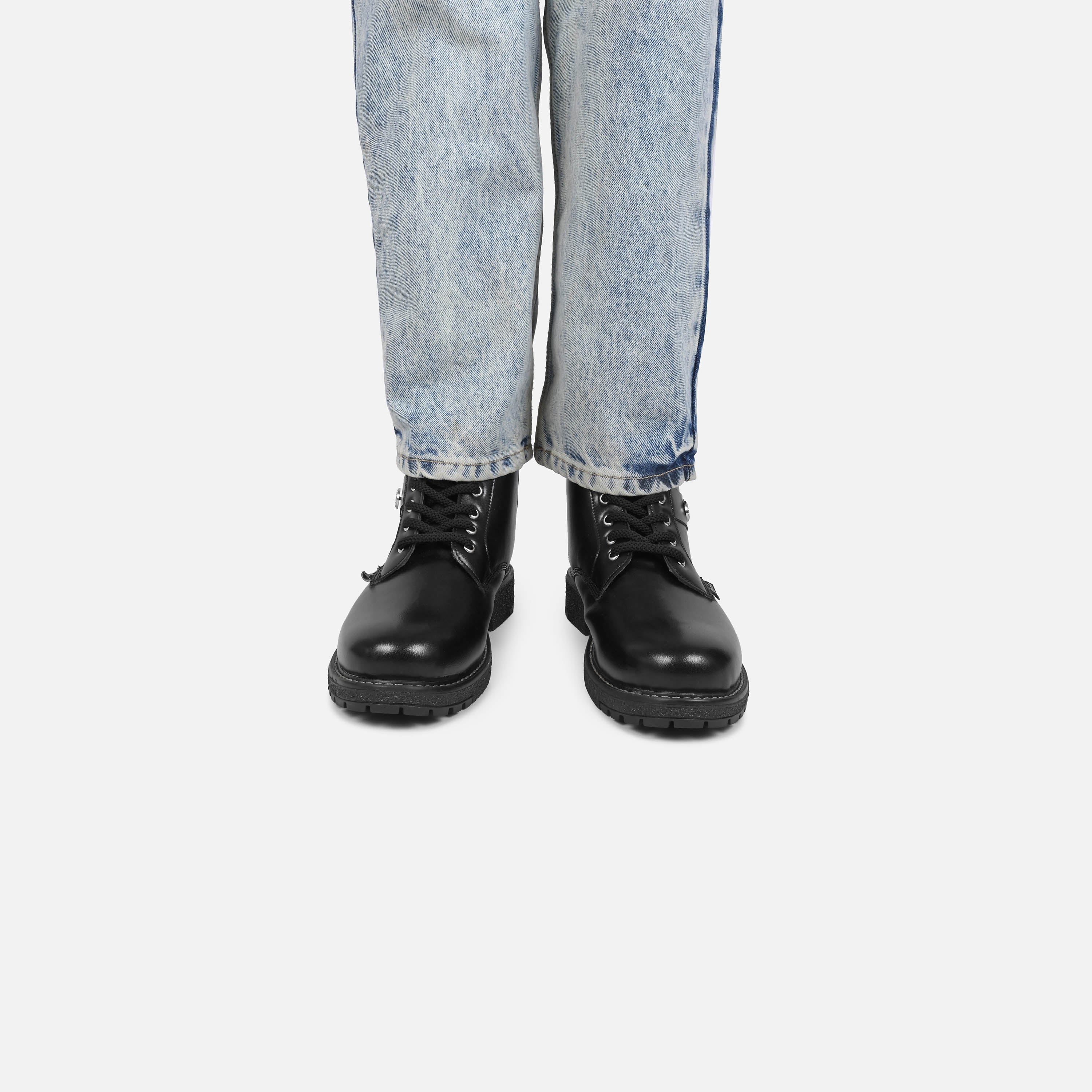 Black boots worn with light blue jeans on a white background