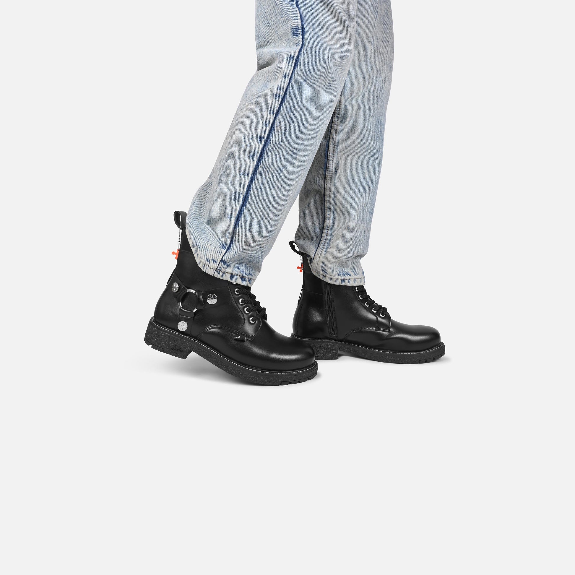 Black leather boots worn with light blue jeans on a white background