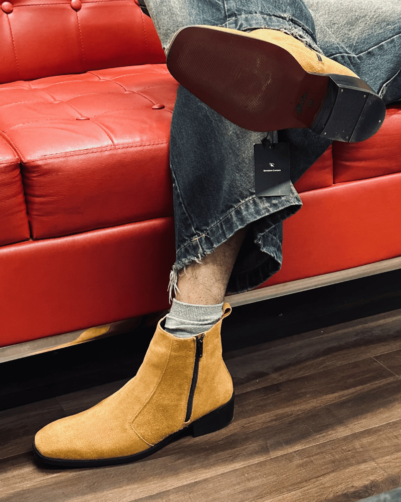 Person wearing tan Chelsea boots with a red sofa in the background