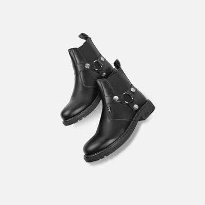 Pair of black leather boots with metallic accents on a light gray background